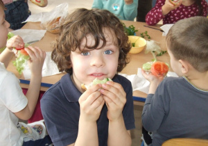 Chłopiec je kanapkę z ogórkiem.