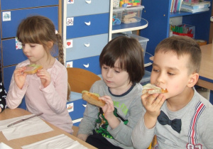 Dzieci jedzą przygotowane przez siebie kanapki.