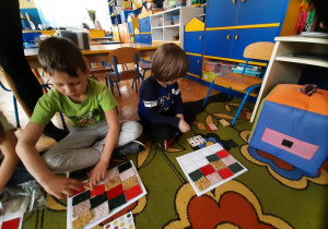 Dzieci układają kolorowe patchworki na kartce.