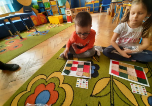 Dzieci układają kolorowe patchworki na kartce.