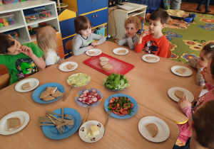 Dzieci przy stolikach z chlebem na talerzach.
