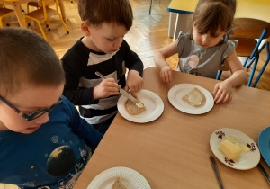 Dzieci smarują chleb masłem.