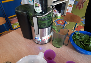 Zielony napój płynie z sokowirówki do pojemnika.