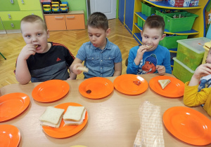 Dzieci jedzą sandwiche.