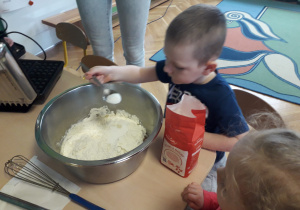 Chłopiec wsypuje cukier do miski.