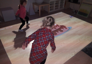 Dziewczynki grają na podłodze interaktywnej w grę.