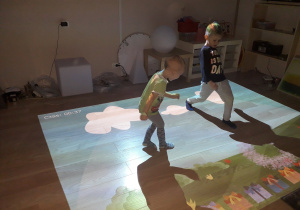 Chłopcy grają w grę na podłodze interaktywnej.