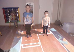 Chłopcy grają w grę na podłodze interaktywnej.