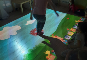Dziewczynka gra na podłodze interaktywnej.