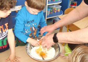 Chłopiec dodaje jajka do miski.