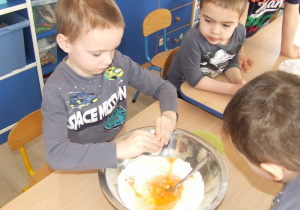 Chłopiec dodaje jajka do miski.
