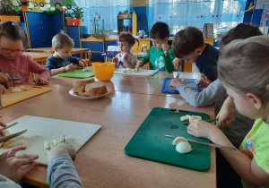 Dzieci kroją na deskach jajko.