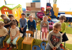 Dzieci siedzą na krzesełkach, czekaja na przedstawienie.