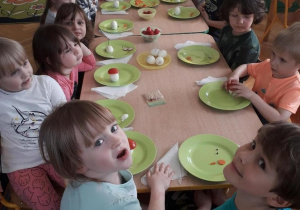 Dzieci siedzą przy stole i wykonują figurki z jajek