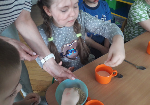 Dzieci wsypują płatki do kubeczka z jogurtem.