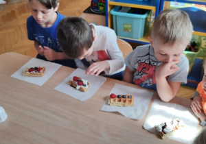 Dzieci dekorują owocami swoje gofry.