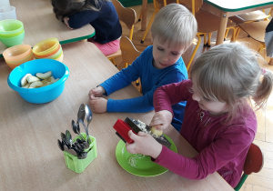 Dzieci trą jabłka na tarce.