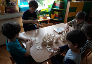 Dzieci składają elementy drewniane.