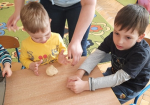 Dzieci robią bułeczki formując w kulki z ciasta drożdżowego.