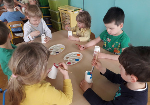 Dzieci malują farbami kubeczki papierowe.