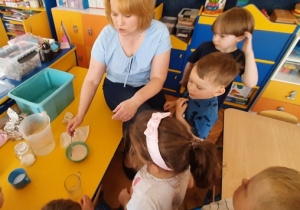 Nauczycielka pokazuje dzieciom w misce rozpuszczone drożdże.