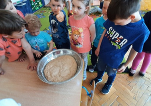 Dzieci ogladają wyrośnięte ciasto w misce.