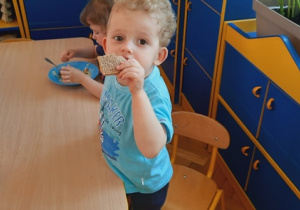 Chłopiec zjada kromkę chleba.