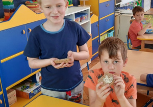 Chłopcy jedzą kromkę chleba z masłem.