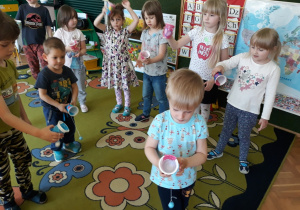 Dzieci wypróbowują zabawkę zręcznościową wykonaną z kubka.