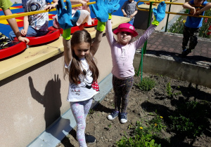 Dzieci pokazują rękawice do prac w ogrodzie.