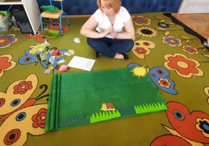 Nauczycielka na dywanie pokazuje teatrzyk sylwet "Wiosna na łące".