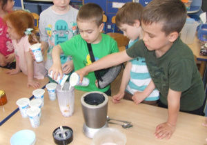 Chłopcy dolewają jogurty do blendera.