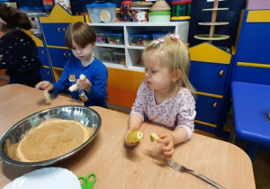 Dzieci obierają banany ze skórki.
