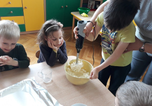 Dzieci wkładają ser do miski.