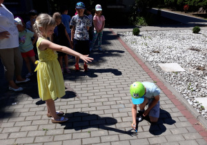 Dzieci obrysowują kredą cień dłoni.