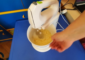 Nauczycielka miksuje masło z cukrem.