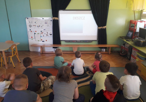 Dzieci oglądają prezentację o zjawiskach atmosferycznych.