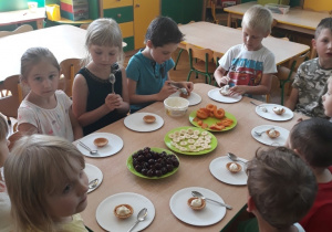 Dzieci przygotowują kruche babeczki z serkiem i owocami.