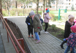 Dzieci zbierają śmieci z ogródka przedszkolnego.