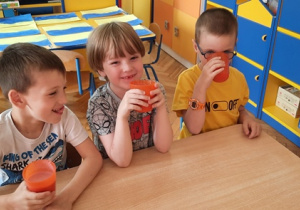 Chłopcy piją koktajl truskawkowy.