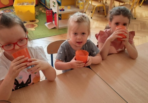Dziewczynki piją koktajl truskawkowy.