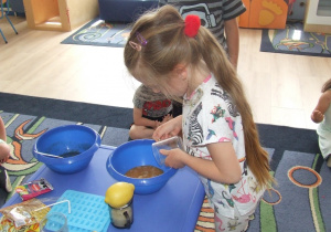 Dziewczynka dolewa soczek do miski.