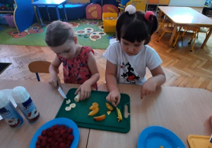 Dziewczynki kroją owoce.