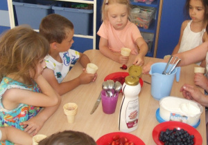 Dzieci przygotowują samodzielnie lody w rożkach.