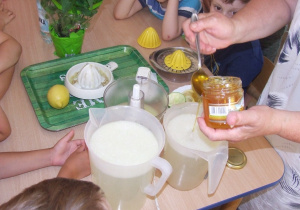 Nauczycielka dodaje miód do wody.