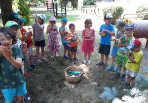 Dzieci stoja w kole trzymają sprzęt do obserwacji owadów.