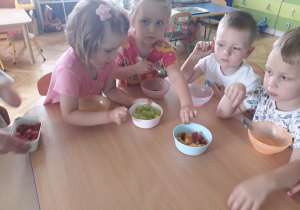 Dzieci wkładają owoce do miseczek.