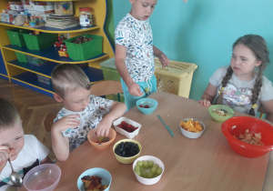 Dzieci wkładają owoce do miseczek.