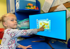Dziewczynka ćwiczy percepcje słuchową z użyciem programu komputerowego.