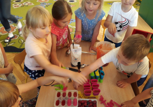 Dzieci zamykają pojemniczki do wyrobu sorbetów owocowych.